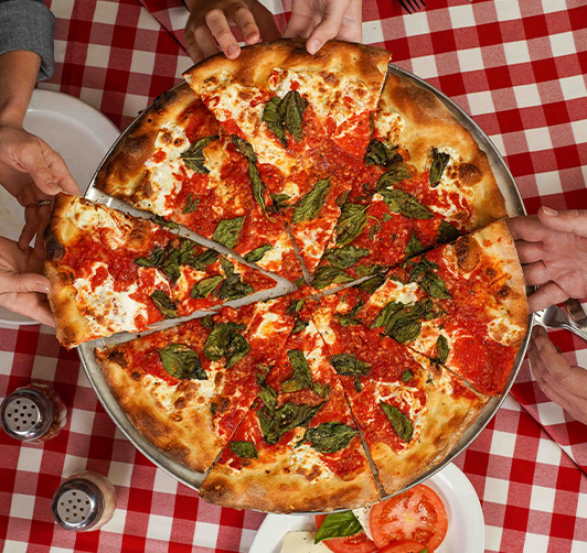 Hands reaching for a pizza