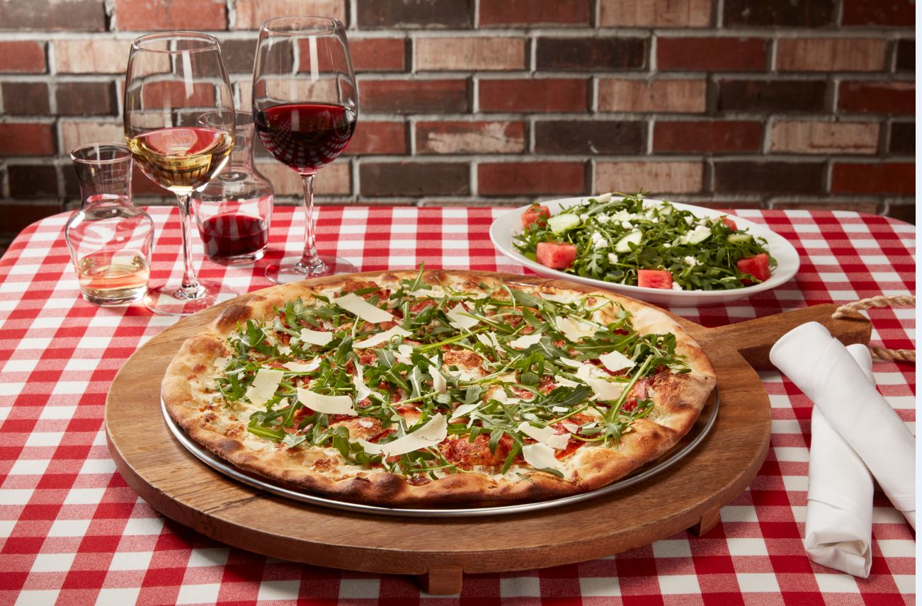 Pizza Salad and wine on a table cloth table.